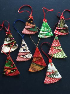 six christmas tree ornaments hanging from red ribbon