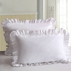 three white pillows with ruffled edges on a bed