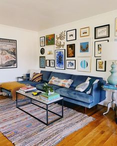 a living room with blue couches and pictures on the wall above it's coffee table