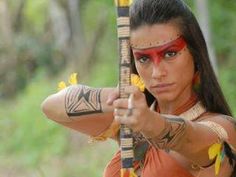 a woman dressed in native american garb holding a bow and arrow with yellow flowers on it