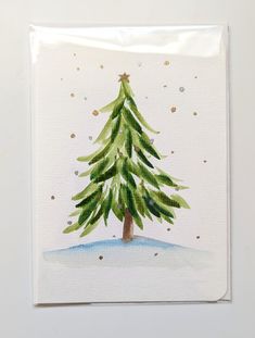 a watercolor painting of a green christmas tree on white paper with gold glitters