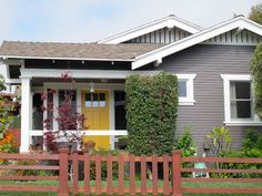 a house with a yellow door and some bushes in front of it on a sunny day