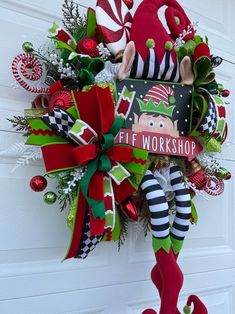 a christmas wreath hanging on the front door with elf's workshop written on it