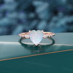 an opal heart shaped ring on top of a green box