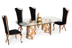 a glass dining table with black chairs and a gold vase on it's side