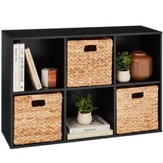 an open book shelf with four baskets and books on the top, along with two planters