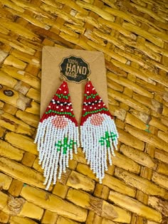 a pair of red, white and green beaded earrings sitting on top of a wooden table