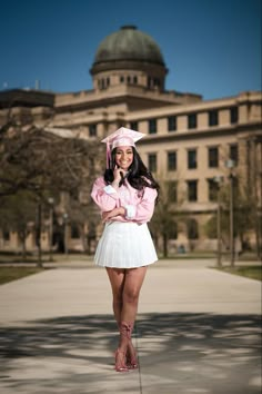 a woman in a pink shirt and white skirt posing for the camera with her hat on