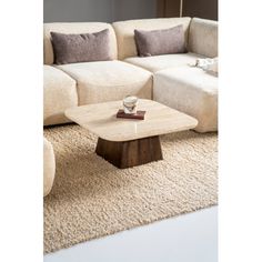 a living room with a couch, coffee table and rugs on the floor in front of it