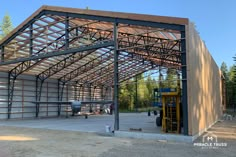 a large metal building sitting on top of a dirt field next to a parking lot