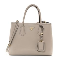 This is an authentic PRADA Saffiano Cuir Small Double Bag in Pomice. This tote is crafted of beautifully textured cross-grain Saffiano leather in beige. This hand bag features rolled leather top handles with a strap keeper, optional adjustable shoulder strap, expandable snap sides, and gold hardware. The top opens to a spacious partitioned interior in black leather interior with a central beige leather dividing flap pocket. 1408046 Prada Saffiano Bag, Prada Double Bag, Prada Bag Saffiano, Mom In Law, Prada Saffiano, Leather Interior, Hand Bag, Leather Top, Flap Pocket