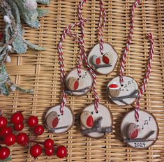 four wooden ornaments with red and white string hanging from them on a wicker table