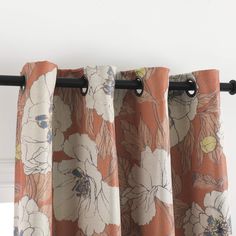 an orange and white flowered curtain hanging from a window sill with black metal rods