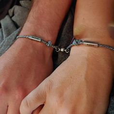 two people wearing bracelets holding each other's hands