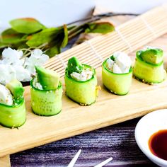 small cucumber slices are arranged on a wooden board next to dipping sauces