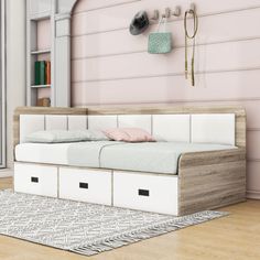 a white daybed with drawers underneath it in a pink room next to a bookcase