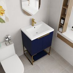 a white toilet sitting next to a blue cabinet in a bathroom under a mirror and sink