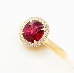 a ring with a red stone surrounded by white diamonds