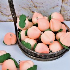 small peaches in a metal bowl with green leaves