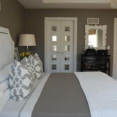 a white bed sitting next to two doors in a bedroom