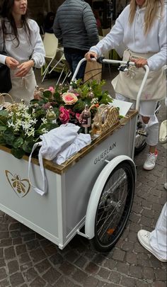 two women pushing a cart with flowers in it