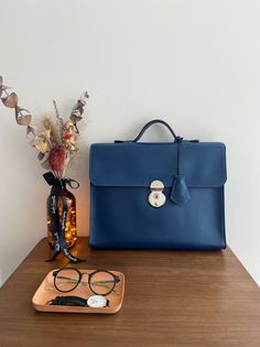 "One and only!  High quality handmade briefcase comes with navy blue colour. Everything is made by hand with great craftsmanship. This simple and minimal design will be good match with business man and woman. Outside of leather is premium italian leather that is very smooth and sleek. And inner lining is dark brown leather which has unique texture. This briefcase has one big pocket that you can put up to 13 inches laptop and two small pockets that you can put notebook or phone, passport and etc. Also I have used high quality japanese lock that gives you more tidy and simple look. Size detail : 13.7\" X 10\" X 2.8\" (35cm X 27cm X 7cm) * Merchandise on display may have some scratches on the surface. This cannot be the reason for refund or return." Elegant Blue Smooth Grain Bags, Formal Blue Bag With Leather Lining, Classic Navy Bag For Formal Occasions, Formal Blue Smooth Grain Bag, Classic Navy Formal Bag, Elegant Blue Satchel With Leather Lining, Modern Navy Bags For Formal Occasions, Timeless Blue Business Bag, Timeless Blue Business Bags