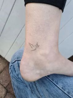 a small tattoo on the ankle of a woman's foot, with a bird flying over it