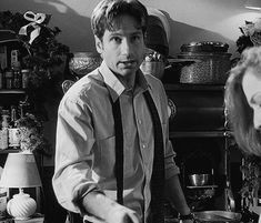 two people standing in a kitchen with pots and pans on the counter, one person wearing a tie