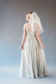 the back of a bride's dress with a veil on her head and shoulders