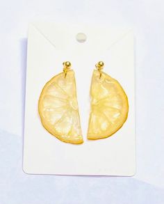 a pair of earrings with lemon slices cut in half on top of a white card