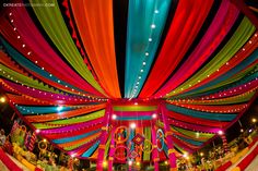 an elaborately decorated stage with colorful draping and lights on the ceiling is seen in this image