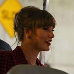 a close up of a person wearing a red and black checkered shirt with an umbrella in the background