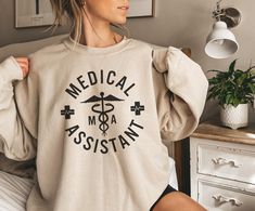 This "medical assistant" sweatshirt would make the perfect graduation gift for new MAs! Want this in a t-shirt instead? You can find it here: https://www.etsy.com/listing/1512431489 * HOW TO ORDER * 1. Look through the photos at the different colors and the sizing chart (all shirts & sweatshirts are unisex sizing) 2. Select the size and color you want from the drop down menus. 3. Choose the quantity you want in that size and color. 4. If applicable, add your custom wording under the "personalization" tab. 5. Click "add to cart" then you can go back and add different colors and sizes the same way if wanted. 6. Click "proceed to check out" 7. Wait for your new favorite shirt or sweatshirt to come in and enjoy! * BELLA CANVAS 3001 SHIRT MATERIALS & WASHING INSTRUCTIONS * - 100% combed and rin Medical Assistant Graduation, Certified Medical Assistant, Usa Sweatshirt, Assistant Gifts, Comfort Colors Sweatshirt, University Logo, Medical Assistant, Printing Labels, Sizing Chart