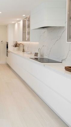 a large kitchen with white cabinets and marble counter tops, along with hardwood flooring