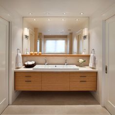 a bathroom with two sinks, mirrors and lights on the wall above them is shown