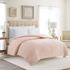 a bed in a bedroom with pink comforter and pillows on top of the bed