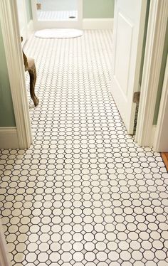 an open door leading to a bathroom with white and black tile on the flooring