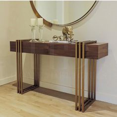 a console table with two candles and a mirror on the wall in front of it