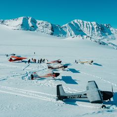 several airplanes are parked in the snow near mountains