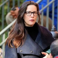 a woman wearing glasses is walking down the street