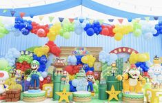 an indoor birthday party with balloons, decorations and mario kartman characters on the stage