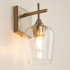 a wall light that is on the side of a wall with a clear glass shade