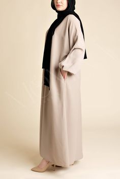 Crafted from the finest nida fabric, this abaya offers a luxurious touch with a relaxed, flowy silhouette that's perfect for any setting. The A-line design ensures a graceful drape, enhancing your silhouette with its effortless charm. The premium Nida fabric used to create these abayas is loved for its lightness, softness, and durability. Barakah is as functional as it is beautiful, featuring side pockets for convenience, elastic cuff sleeves for wudhu friendliness, and a back zip closure for a Chic Long Abaya For Eid, Elegant Long Beige Abaya, Elegant Beige Abaya For Eid, Elegant Beige Long Thobe, Elegant Long Beige Thobe, Chic Long Abaya For Formal Occasions, Elegant Long Outerwear For Eid, Elegant Long Beige Kaftan, Formal Modest Thobe