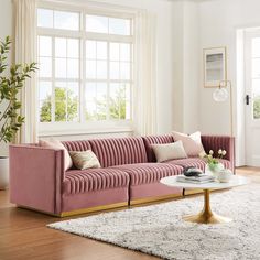 a living room with pink velvet couches and white rugs on the wooden floor