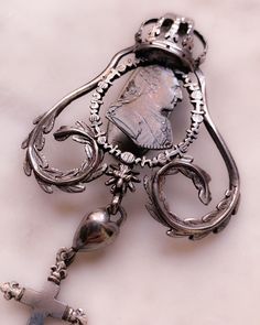 During the Georgian era, when new sources of silver were found in silver-rich South America, the production of silver jewelry flourished. Silver was the most popular type of metal for making jewelry in Europe at the time and has remained one of our most prized jewelry-making materials to this day. Wrought with symbolism, this unreal example features a customized drop of symbolism including a heart, a cross, an anchor, and a steel-cut anchor. The top element features a large crown and laurel leav Baroque Jewelry With Historical Design For Formal Occasions, Baroque Historical Jewelry For Formal Occasions, Baroque Historical Design Jewelry For Formal Occasions, Formal Baroque Hallmarked Jewelry, Antique Silver Baroque Style Jewelry, Antique Silver Baroque Jewelry, Ornate Baroque Silver Jewelry, Victorian White Gold Jewelry For Jewelry Making, Ornate Baroque Jewelry For Anniversary