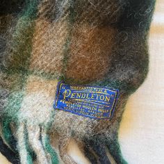 a green and brown plaid blanket with a label on it that says pendleton written in blue