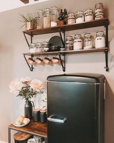 a refrigerator and shelves in a kitchen with jars on the wall above it, along with other items