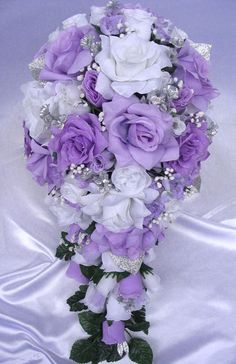 a bridal bouquet with purple and white flowers on a silver satin tableclothed background