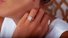 a woman wearing a diamond ring and white shirt with her hand on her shoulder, looking at the camera