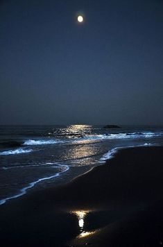 the moon shines brightly in the night sky over the ocean and beach as waves wash on the shore